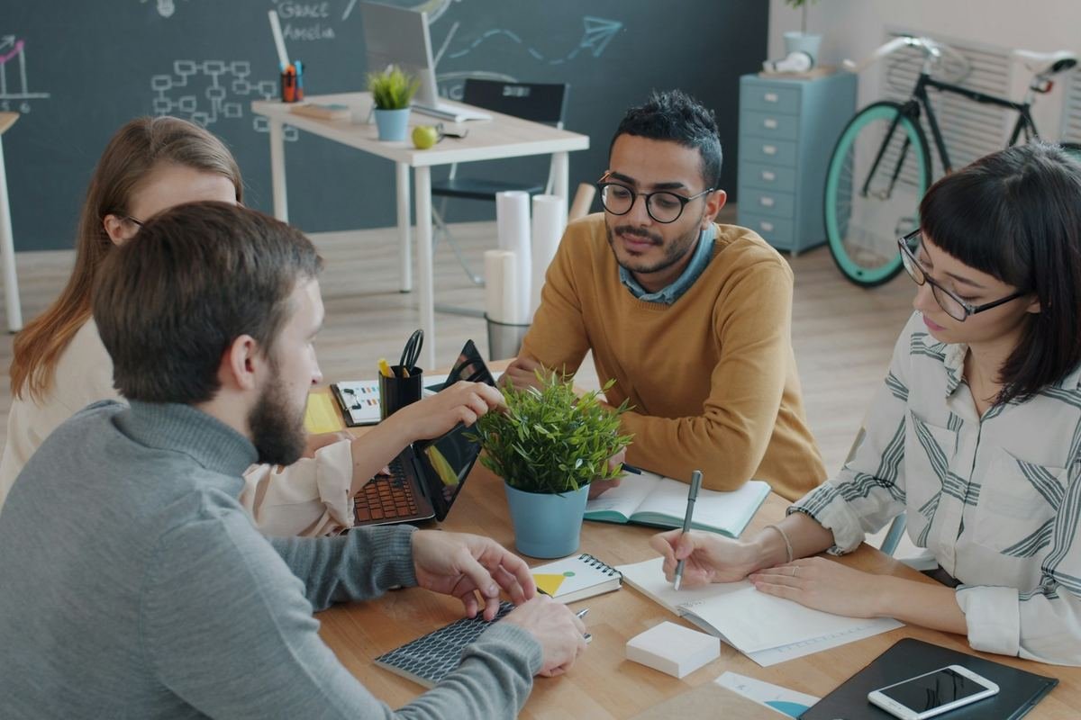 A small team talking around a table in a bright office
